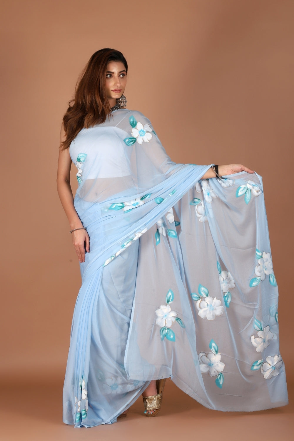 Model in sky blue chiffon saree with hand-painted white flowers