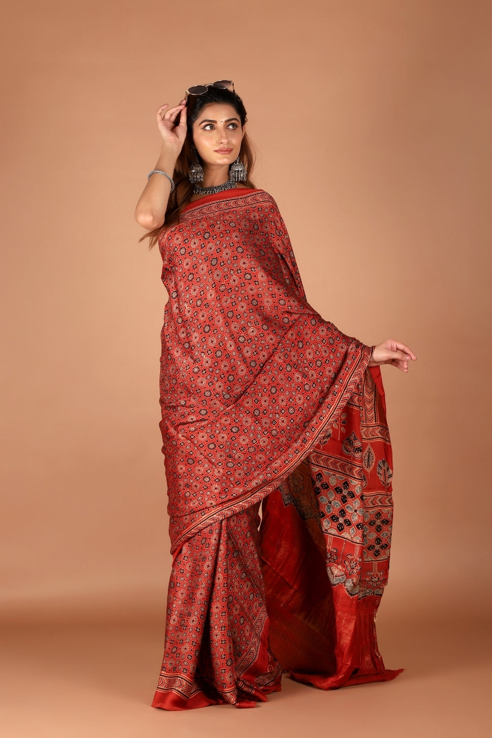 Model in red Ajrakh modal silk saree with shimmering zari palla